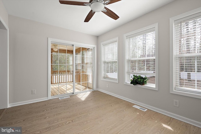 empty room featuring visible vents, ceiling fan, baseboards, and wood finished floors