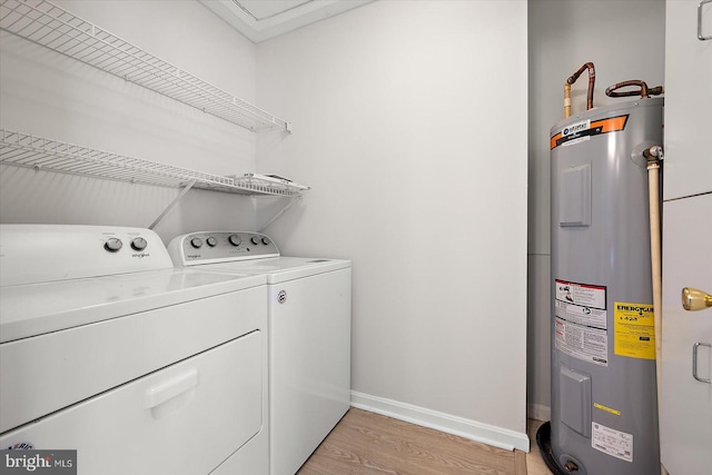 laundry area with laundry area, baseboards, water heater, light wood-type flooring, and washing machine and clothes dryer