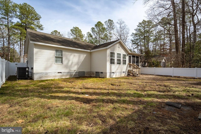 rear view of house with central air condition unit, a lawn, entry steps, crawl space, and a fenced backyard