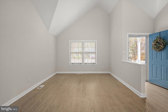 unfurnished room with lofted ceiling, baseboards, visible vents, and wood finished floors