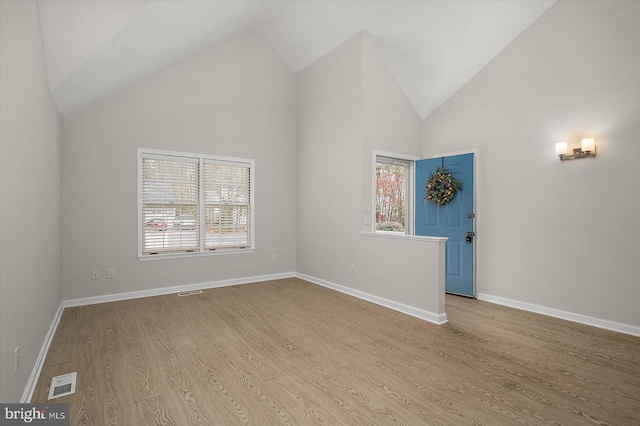 unfurnished room with high vaulted ceiling, baseboards, visible vents, and wood finished floors