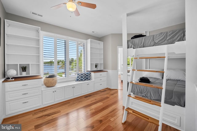 bedroom featuring ceiling fan, a water view, and light hardwood / wood-style flooring