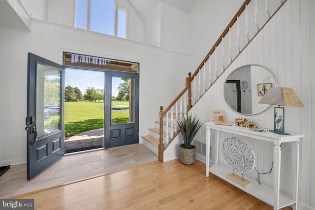 foyer entrance with wood-type flooring and high vaulted ceiling