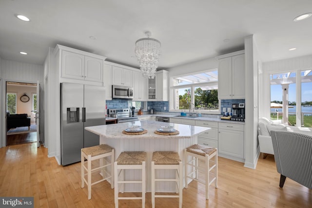 kitchen featuring white cabinetry, sink, a kitchen breakfast bar, a kitchen island, and appliances with stainless steel finishes