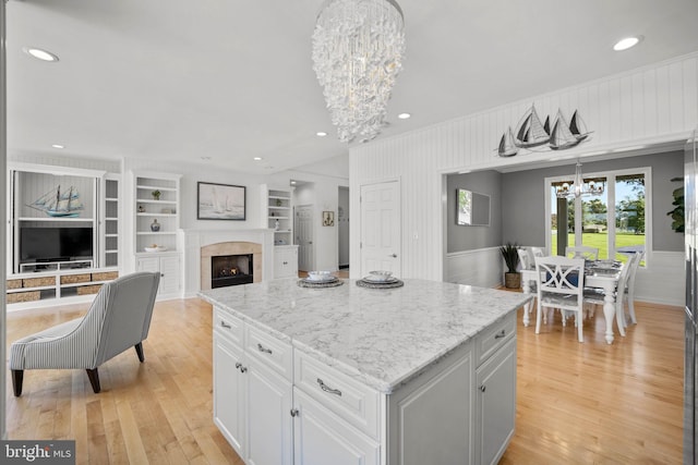 kitchen featuring built in shelves, white cabinetry, a center island, pendant lighting, and light wood-type flooring