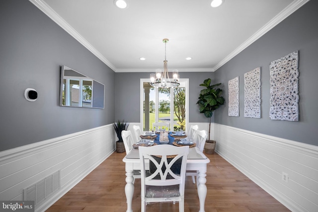 dining space featuring hardwood / wood-style flooring, ornamental molding, and a chandelier