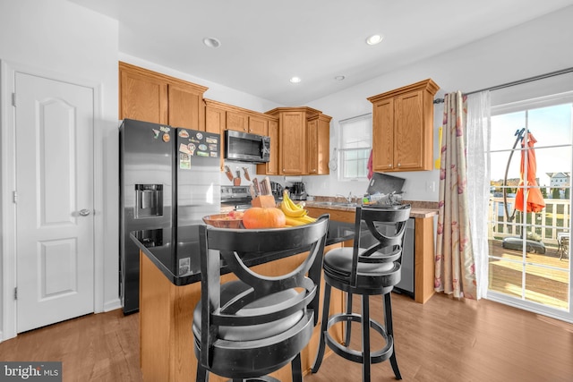 kitchen featuring stainless steel appliances, recessed lighting, a kitchen island, and wood finished floors