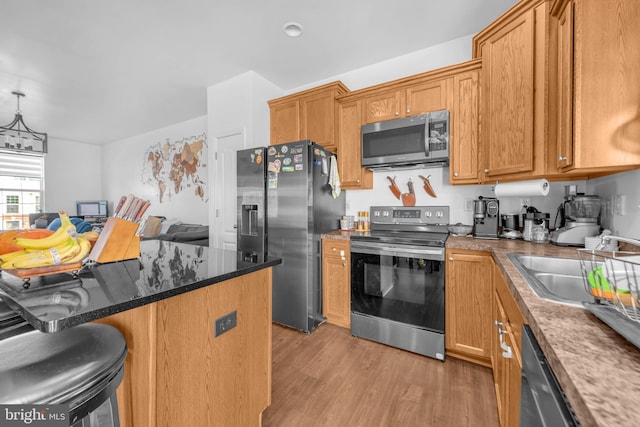 kitchen with stainless steel appliances, a breakfast bar area, brown cabinetry, and light wood-style floors