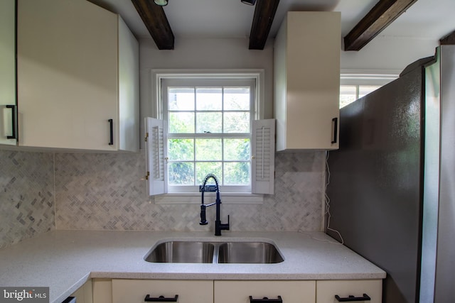 kitchen featuring tasteful backsplash, a wealth of natural light, sink, white cabinets, and stainless steel refrigerator