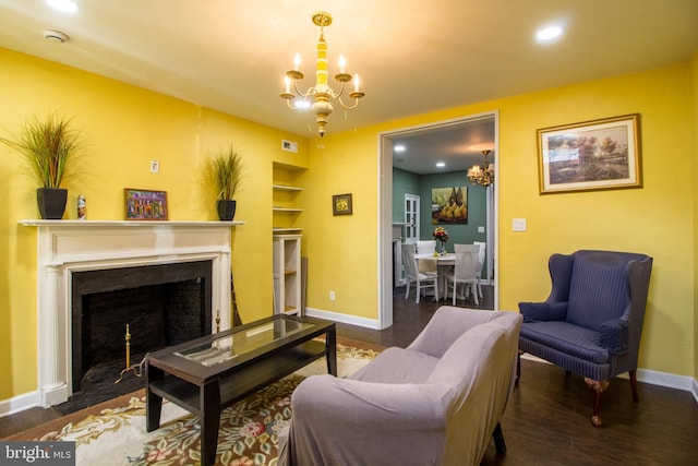 living room featuring built in shelves, dark hardwood / wood-style flooring, and an inviting chandelier