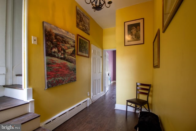 corridor with a baseboard radiator, dark wood-type flooring, and a notable chandelier