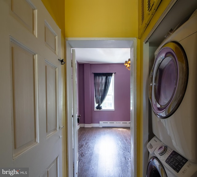 clothes washing area with a chandelier, hardwood / wood-style floors, stacked washing maching and dryer, and a baseboard heating unit