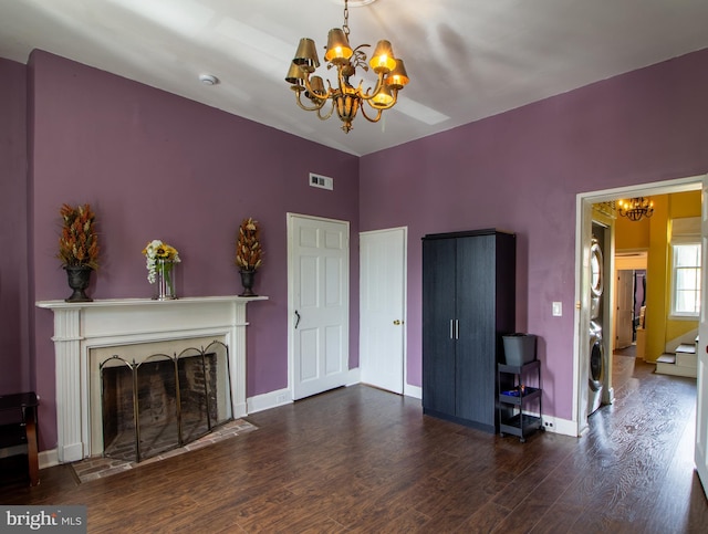 unfurnished living room featuring a chandelier, dark wood-type flooring, and washer / dryer