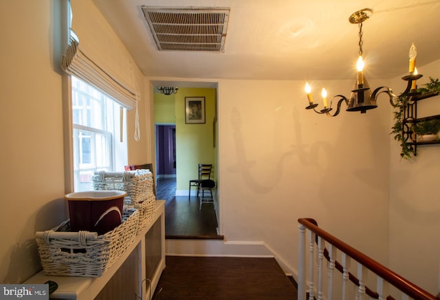 hallway featuring dark wood-type flooring and an inviting chandelier