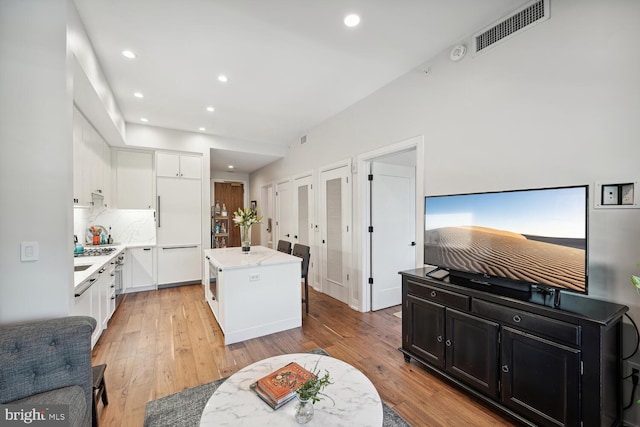 kitchen with white cabinets, a kitchen island, and light wood-type flooring