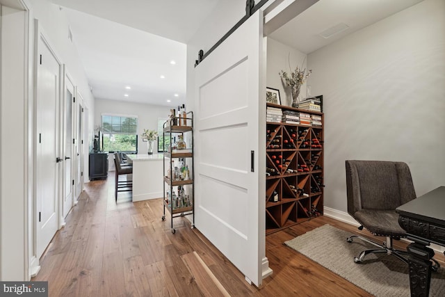 office with a barn door and hardwood / wood-style flooring