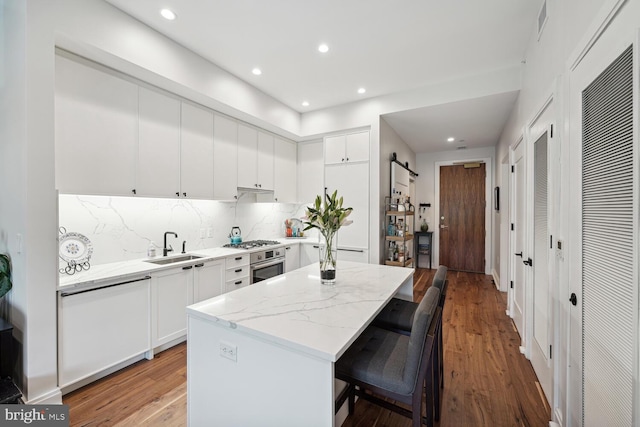 kitchen featuring white cabinetry, sink, stainless steel appliances, a barn door, and light stone counters