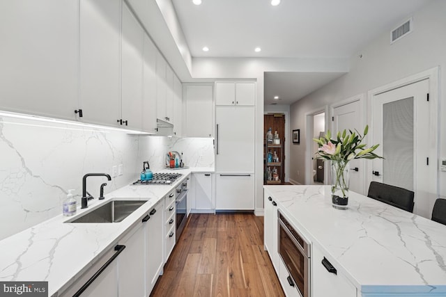 kitchen with appliances with stainless steel finishes, backsplash, light stone counters, sink, and white cabinets