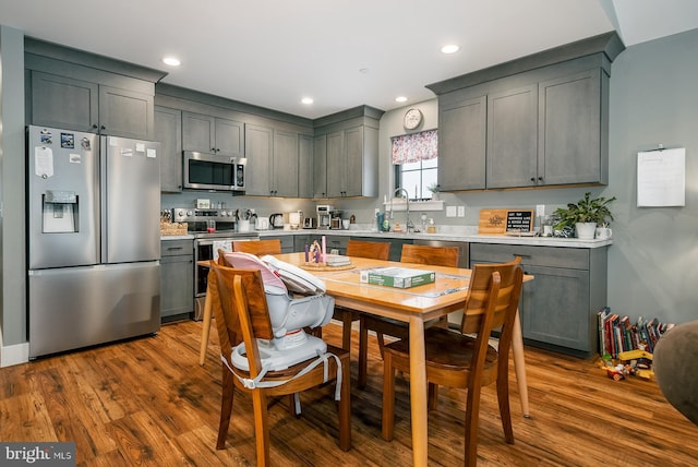 kitchen with sink, dark wood-type flooring, gray cabinetry, and appliances with stainless steel finishes