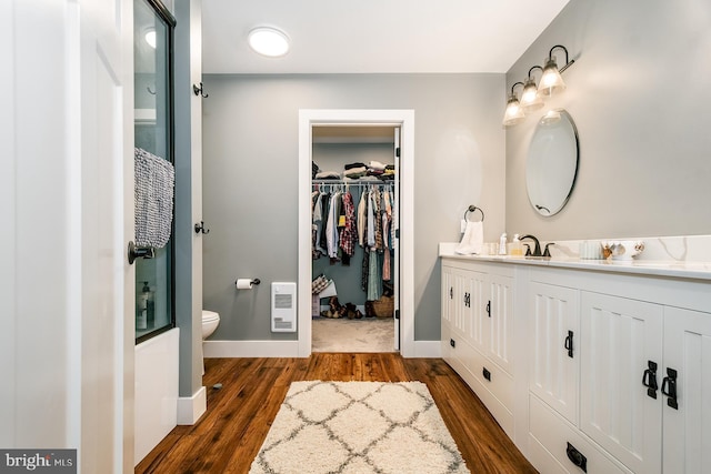 bathroom with vanity, heating unit, hardwood / wood-style floors, and toilet