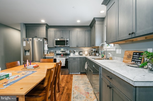 kitchen featuring gray cabinetry, sink, light hardwood / wood-style floors, and appliances with stainless steel finishes