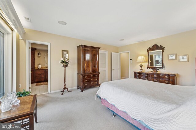 bedroom featuring ensuite bathroom and light colored carpet