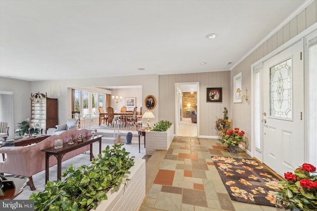 foyer featuring a notable chandelier, wood walls, and ornamental molding