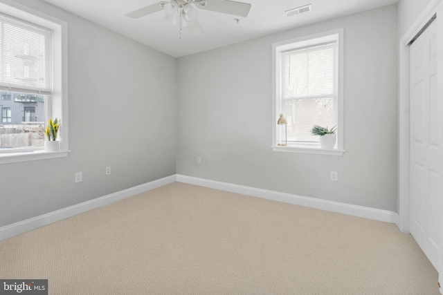 carpeted empty room featuring ceiling fan and plenty of natural light