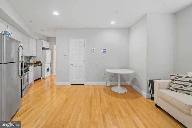 interior space with light wood-type flooring and stacked washing maching and dryer