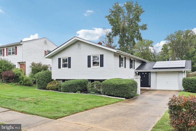 tri-level home featuring solar panels, a garage, and a front yard