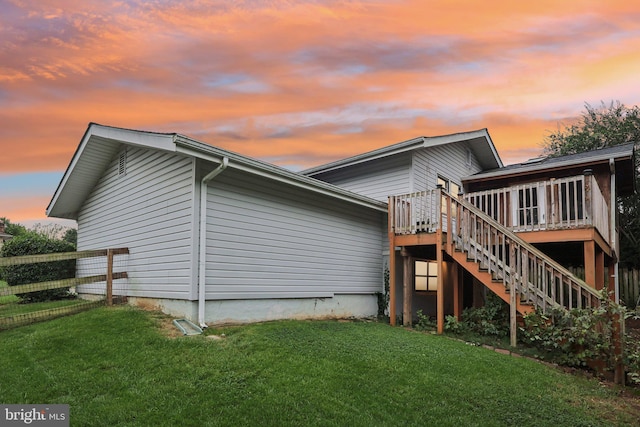 back house at dusk featuring a yard and a deck