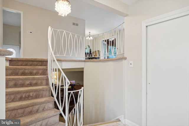 stairway featuring a notable chandelier