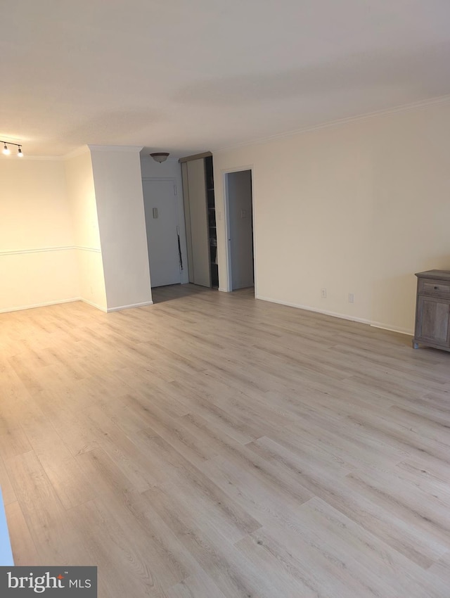 empty room with light wood-type flooring and ornamental molding