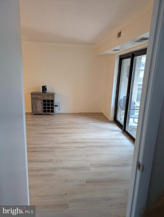 spare room featuring crown molding and light hardwood / wood-style floors