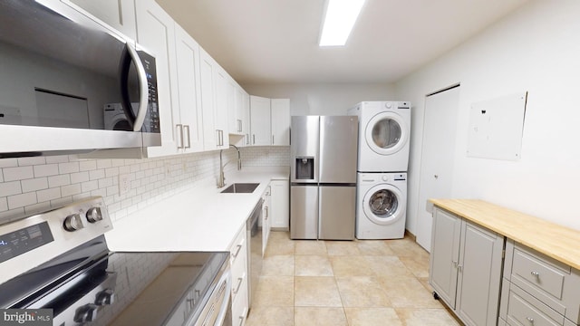 clothes washing area with electric panel, sink, light tile patterned flooring, and stacked washer and clothes dryer