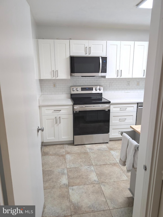 kitchen featuring decorative backsplash, white cabinets, and appliances with stainless steel finishes