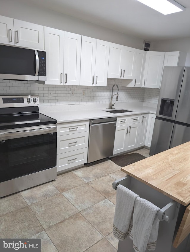 kitchen with decorative backsplash, sink, white cabinetry, and stainless steel appliances