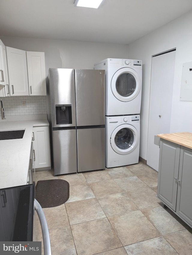 washroom featuring stacked washer / dryer and sink