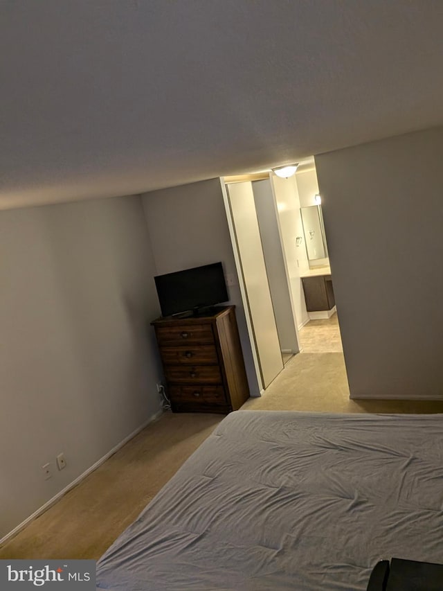 unfurnished bedroom featuring light colored carpet and ensuite bath