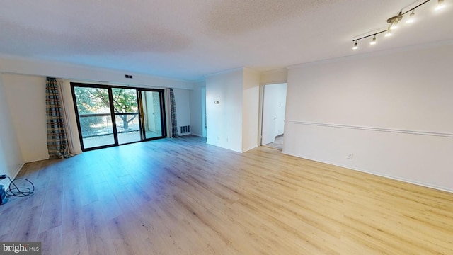 unfurnished room featuring a textured ceiling and light hardwood / wood-style flooring