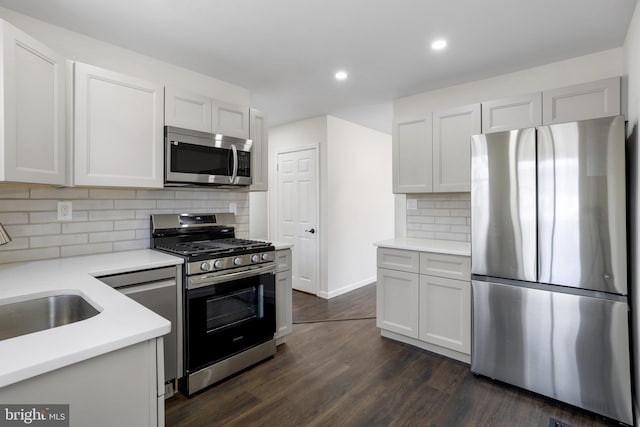 kitchen featuring white cabinetry, stainless steel appliances, dark wood-type flooring, and tasteful backsplash