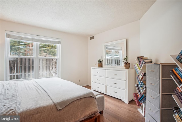 bedroom featuring light wood-type flooring and a textured ceiling