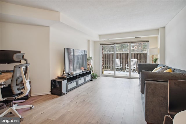 living room featuring light wood-type flooring and a textured ceiling