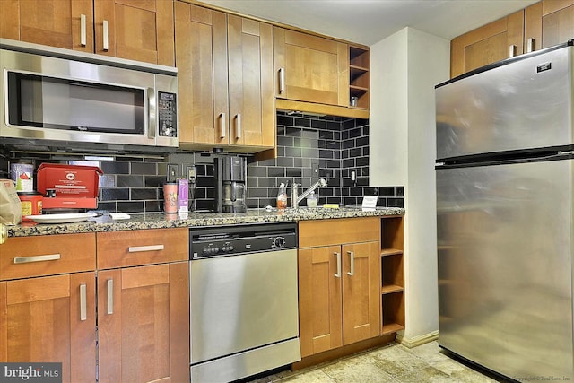 kitchen with light stone countertops, appliances with stainless steel finishes, sink, and tasteful backsplash