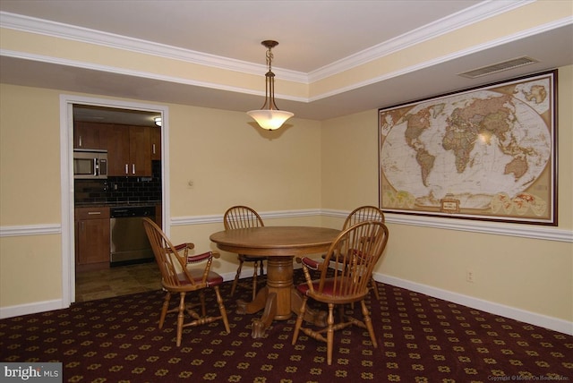 carpeted dining room with a tray ceiling and crown molding