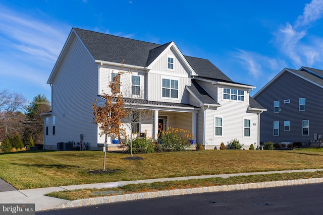 view of front of home with covered porch, a front yard, and central AC