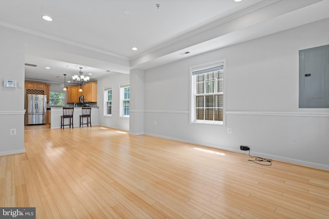 unfurnished living room with electric panel, ornamental molding, light hardwood / wood-style floors, and an inviting chandelier