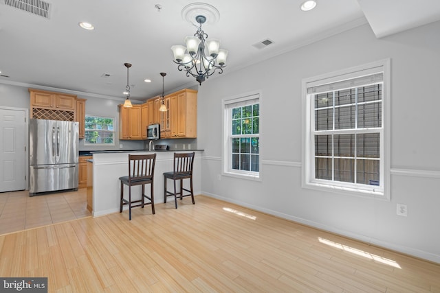 kitchen with an inviting chandelier, a kitchen breakfast bar, hanging light fixtures, kitchen peninsula, and stainless steel appliances