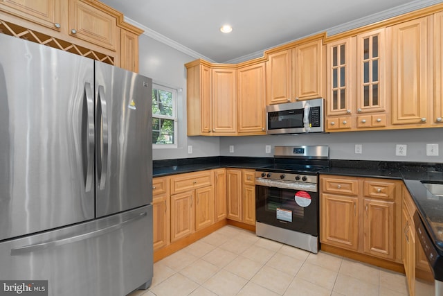 kitchen with light tile patterned flooring, dark stone countertops, ornamental molding, and stainless steel appliances