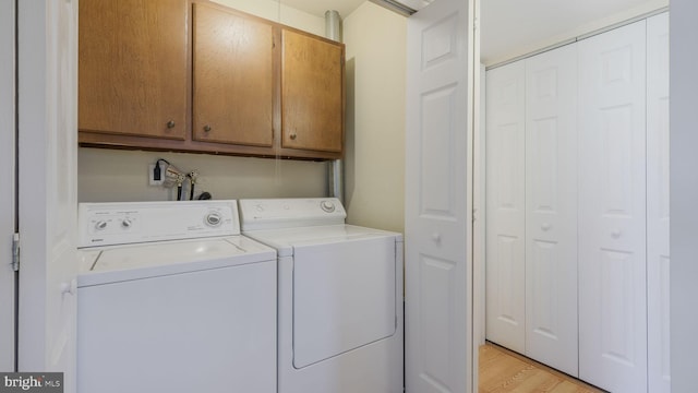 washroom with cabinets, separate washer and dryer, and light hardwood / wood-style floors